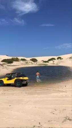 Buggy e pessoa num lago entre as dunas